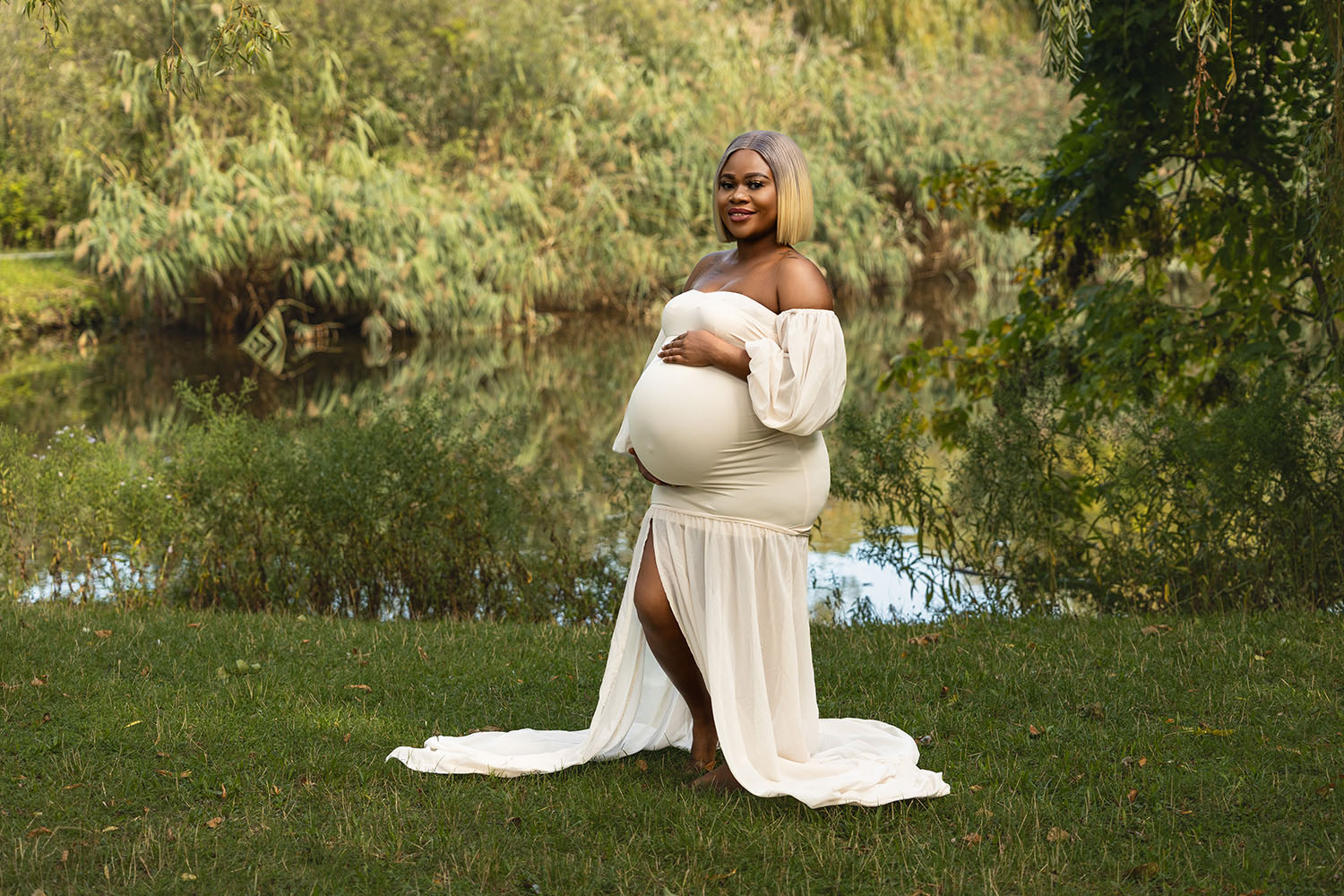 Eine Schwangere im Park vor einem Teich bei einem Babybauch Shooting.