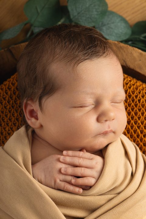 Ein Baby schläft in einer Holzschale für Neugeborenenfotos.