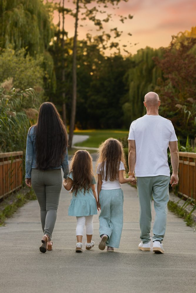 Eine Familie spaziert auf einer Brücke im Park bei einem Fotoshooting am Abend.
